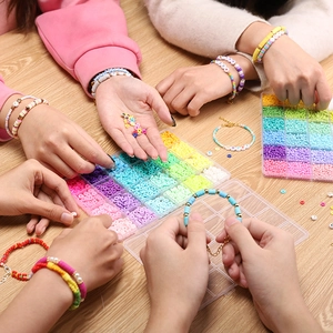 Mensen maken DIY-armbanden met kleurrijke heishi-kralen en letterkralen op houten tafel