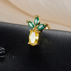 Macro shot of pineapple stud earring with green and yellow gemstones on a satin backdrop