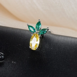 Macro shot of pineapple stud earring with yellow gemstone and green crystal leaves