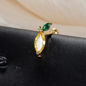 Macro view of gold fruit-shaped ear stud with yellow and green marquise zircon