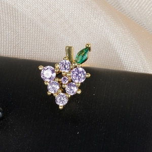 Detailed macro shot of grape-shaped earring with purple zircons and green leaf detail