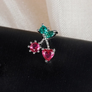 Detailed close-up of cherry stud earring with red heart stones and green gem leaves