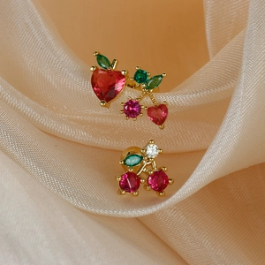 Golden cherry stud earrings set with red heart crystals on silk champagne fabric