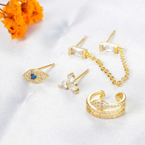 Goldenes Evil Eye Ohrring Set mit Zirkonia Steckern und Ketten auf weißer Seide