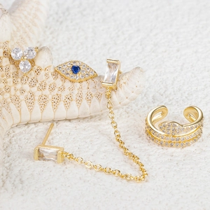Makroaufnahme von goldenem Evil-Eye-Ohrring-Set mit blauen Zirkonia auf weißem Hintergrund