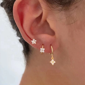 Close-up of gold geometric floral earrings set with zircon micro-pave on a model ear
