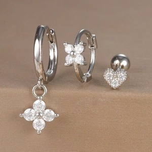Detail of three-piece silver earrings set with zircon flowers and heart stud