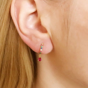 Close-up of gold hoop earring with colorful rhinestones and red pear-cut drop stone