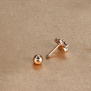 Detail of rose gold cartilage stud with three black cubic zirconia on silk fabric