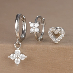 Detailed close-up of a silver earring set with floral pendants and heart studs