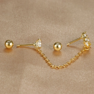 Macro-opname van 18K gouden dubbele piercing oorbellen met zirkoon en fijne O-ketting