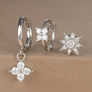 Detailed macro view of silver hoop earrings set with zircon flower and star pendants
