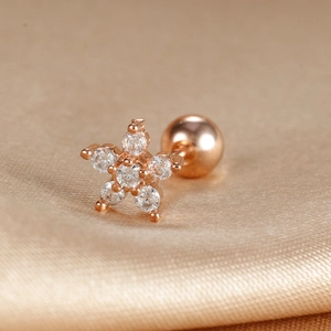 Macro shot of rose gold star stud earring with clear zircons on champagne satin