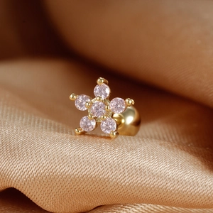 Gold star cartilage stud earring with pink zircon stones on gold satin background