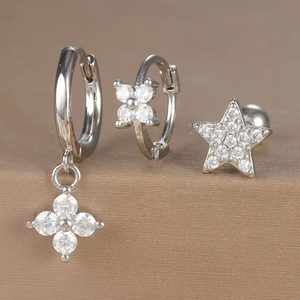 Macro detail of silver zircon earrings set featuring floral charms and star stud designs