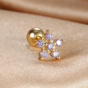Macro shot of gold star piercing earring with lavender zircon and screw ball back