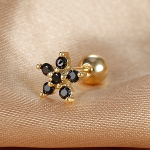 Close-up of golden flower stud earring with black zircon stones and screw back on silk