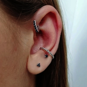 Detalle de pendientes de plata con circonitas negras y un brazalete de oreja trenzado