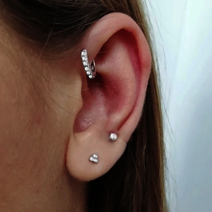 Detalle de set de tres pendientes de plata con circonitas en oreja de modelo
