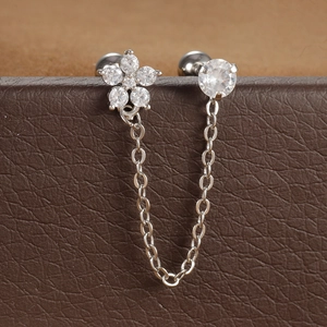 Macro-opname van een zilveren dubbele piercing ketting oorbel op een bruine lederen doos
