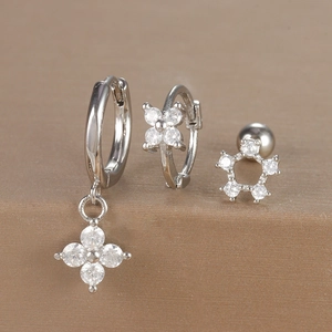 Close-up of three-piece silver earrings set with zircon flower and star designs
