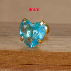 Close-up of 8mm light blue heart zircon stud with gold screw back on wood surface