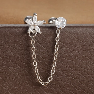 Detail van dubbele piercing oorbellen met zirkonia bloem en fijne zilverkleurige ketting