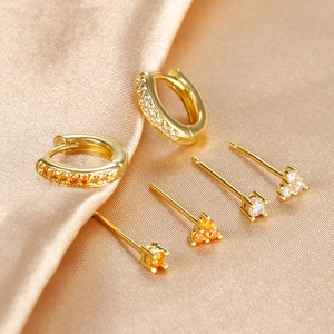 Conjunto de pendientes dorados con cristales naranjas sobre seda color champán