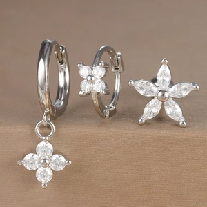Macro view of three-piece earring set with clover pendant, hoop, and zircon flower stud