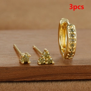 Detalle del juego de 3 pendientes dorados con cristales verde oliva sobre madera