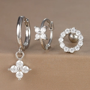 Detail of silver earring set featuring flower charms and sparkling white zircon hoops