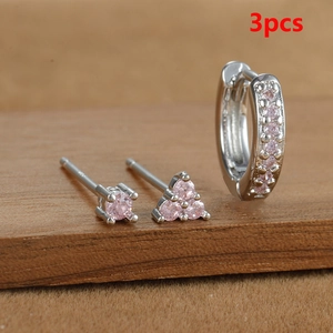 Detalle de set de 3 pendientes de plata con circonitas rosas sobre soporte de madera