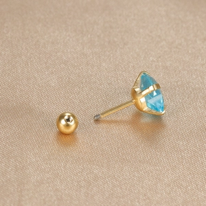 Macro view of blue zircon heart ear stud with screw back closure in gold finish