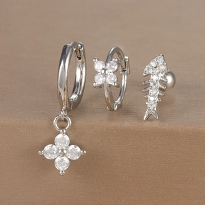 Detailed shot of silver flower and fishbone earrings set with sparkling zircons