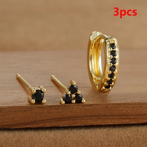 Primer plano de un set de 3 pendientes dorados con circonitas negras en madera