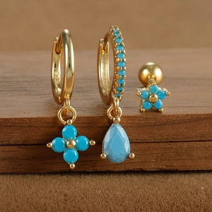 Macro shot of 925 silver gold-plated hoop earrings with turquoise flower pendants