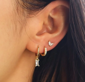 Primer plano de set de earcuffs bañados en oro con circonitas verdes y claras
