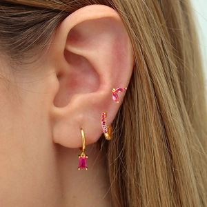 Detalle de pendientes de latón chapado en oro con circonitas rosas en la oreja
