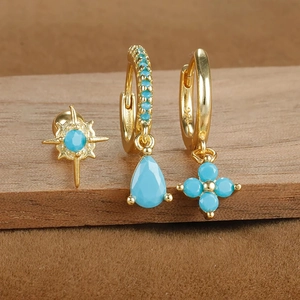 Detail of three-piece gold S925 silver earrings set with turquoise blue star and flower charms