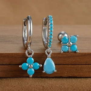 Detailed close-up of S925 silver turquoise clover earrings set on a wooden surface