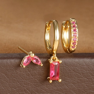 Detalle macro de pendientes de aro bañados en oro y tachuelas con circón rosa en soporte