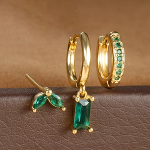 Detalle de set de pendientes dorados con circonitas verde esmeralda en formas geométricas