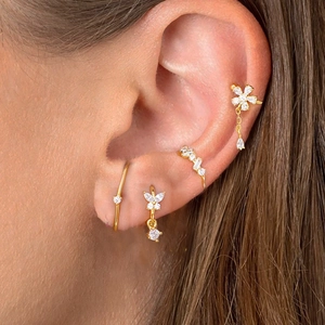 Close-up of elegant gold plated ear cuff set with zirconia flowers and tassels