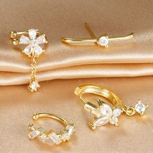 Detail view of gold flower earrings set with zircon tassels on champagne silk