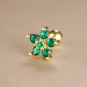 Macro detail of gold-plated green zircon flower cartilage stud with screw ball back