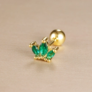 Close-up of golden crown cartilage stud with green marquise stones and screw ball back