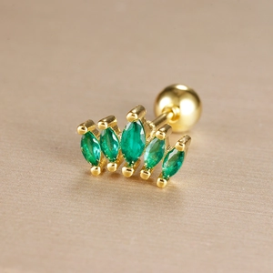 Macro detail of crown shaped ear stud with green marquise stones and gold plating