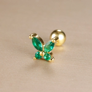 Detailed macro view of golden butterfly earring with green zircon and screw ball back