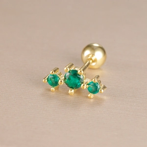 Macro view of gold plated crown cartilage stud with three green zircons and screw ball