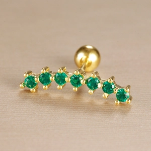 Detailed close-up of curved gold ear stud with seven green zircon stones and screw back ball